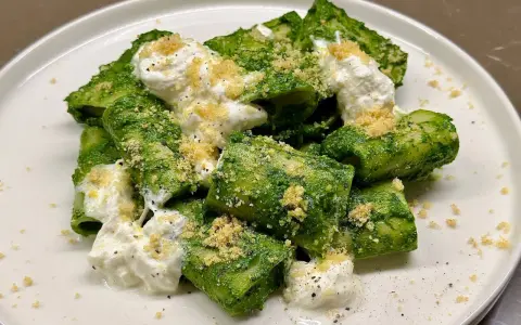 Paccheri conditi con un vibrante pesto di cavolo nero, arricchiti da ricotta fresca e pangrattato croccante.