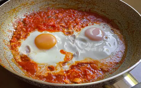 Uova in purgatorio, due uova cotte in una salsa rossa piccante, in una padella.