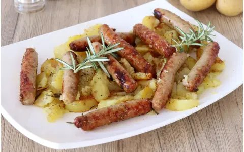 Salsiccia e patate al forno, un piatto rustico e saporito, con rosmarino fresco che profuma il tutto.