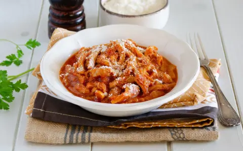 Un invitante piatto di trippa alla parmigiana, cosparso di formaggio grattugiato, pronto per essere gustato.