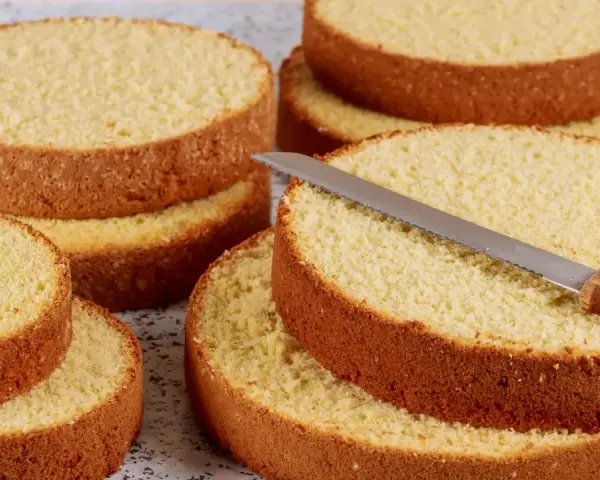 Dischi di pan di spagna sofficissimo con lievito, pronti per essere farciti. Una lama di coltello affilata riposa su uno strato.