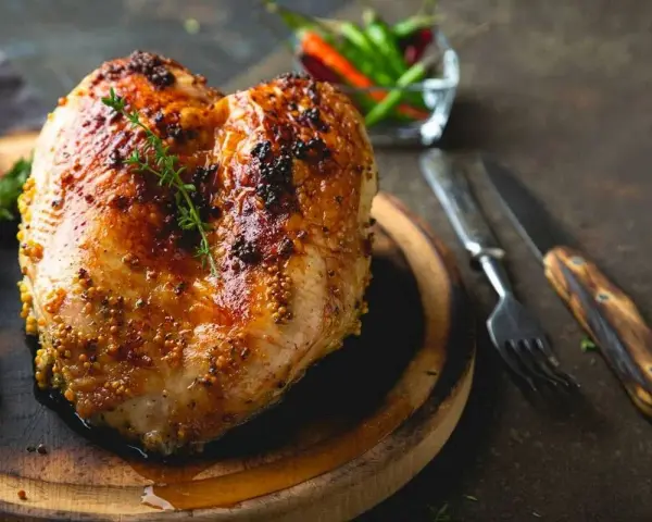 Petto di pollo al forno dorato e succulento, condito con senape e erbe aromatiche, pronto per essere gustato.