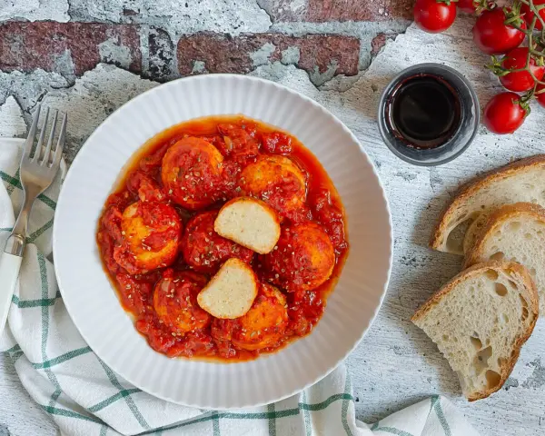 Polpette di ricotta al sugo, morbide e saporite, servite con pane casereccio e pomodorini freschi.