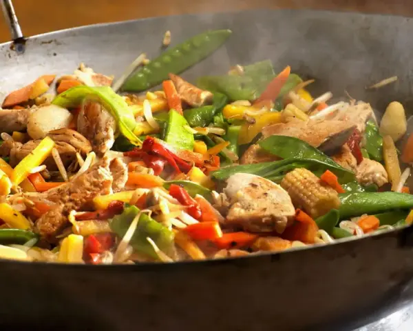 Straccetti di pollo saltati in padella con verdure colorate: piselli, carote, peperoni e germogli.