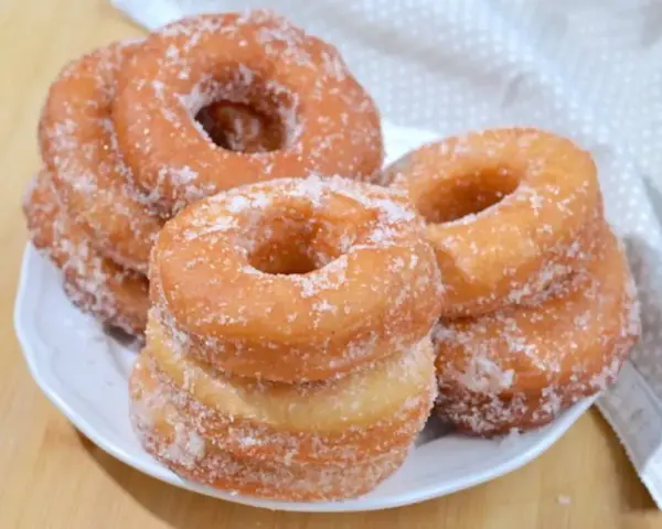 Ciambelle fritte dorate, cosparse di zucchero, pronte per essere gustate. Una deliziosa ricetta ciambelle fritte per ogni occasione.