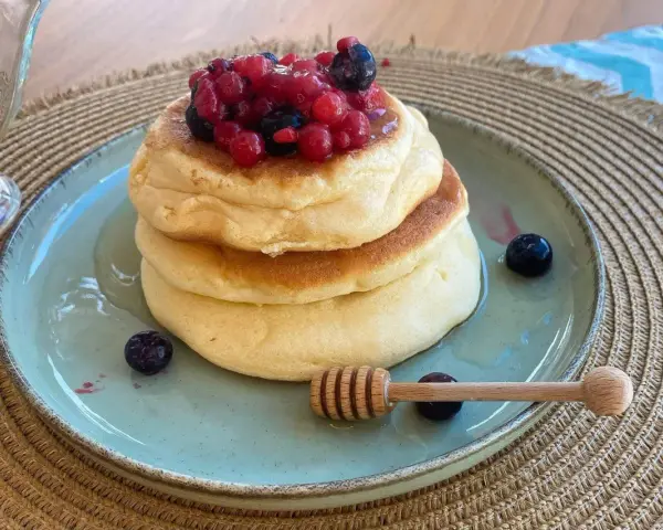 Pancake con albumi soffici, guarniti con frutti di bosco e miele. Un dolce leggero e goloso.