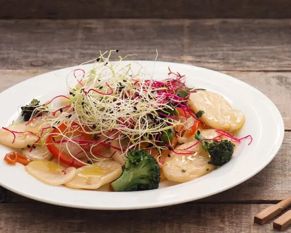 Gnocchi di riso con verdure croccanti e germogli freschi, un piatto leggero e colorato.