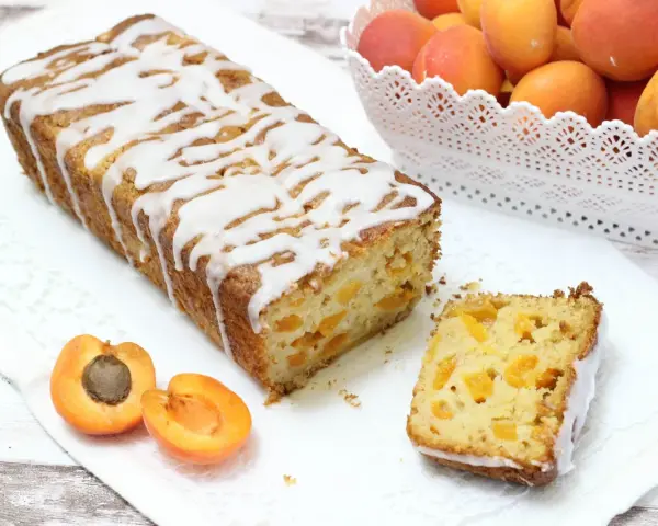 Plumcake senza uova con albicocche fresche, glassato con una leggera copertura bianca. Un dolce soffice e profumato, perfetto per la colazione o la merenda.