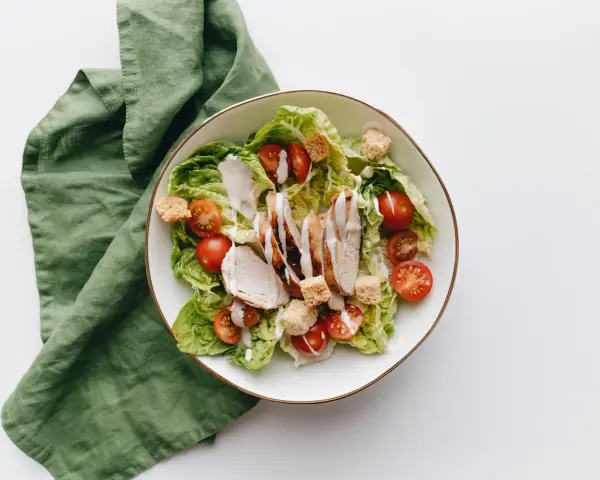 Deliziosa insalata di pollo con lattuga croccante, pomodorini succosi e crostini, condita con una cremosa salsa.