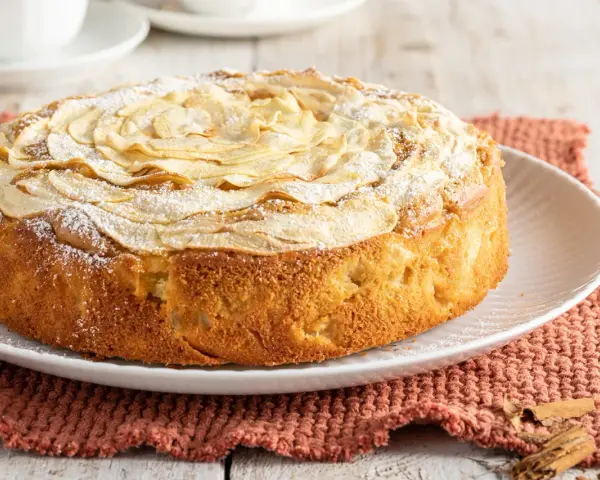 Deliziosa torta di mele senza burro, con mele a rosa sulla superficie e una spolverata di zucchero a velo. Perfetta per una colazione leggera.