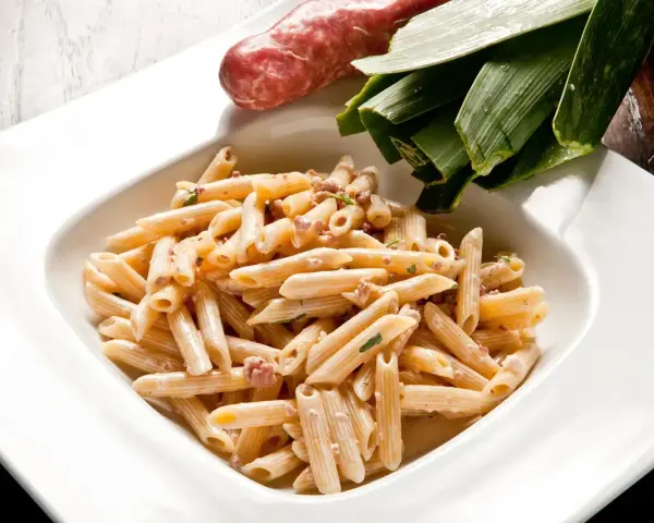 Penne cremose con salsiccia e verdure, un piatto di pasta alla norcina pronto per essere gustato.