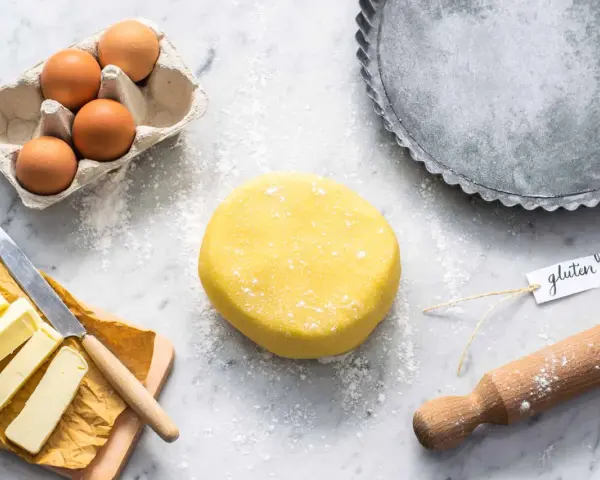 Impasto giallo brillante per una deliziosa pasta frolla senza glutine, pronto con uova, burro e una teglia.