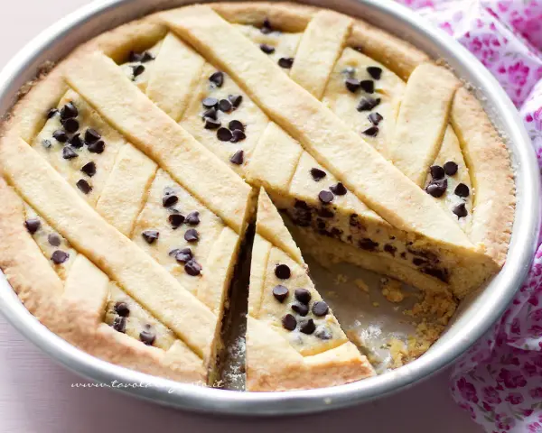 Deliziosa crostata ricotta e cioccolato con un reticolo di pasta frolla e gocce di cioccolato fondente.