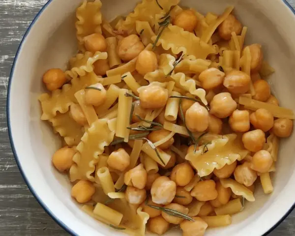 Un piatto invitante di pasta e ceci, con pasta corta e ceci dorati, guarnito con rosmarino fresco.