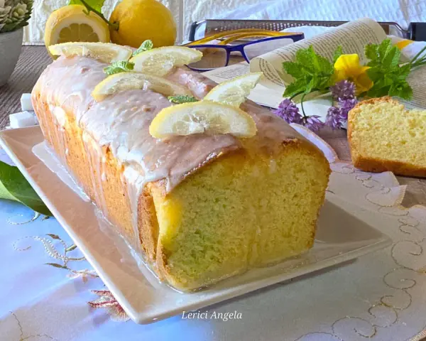 Un soffice plumcake al limone glassato, decorato con fette di limone e menta. Perfetto per una pausa golosa.