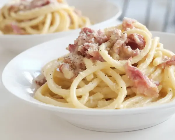 Un piatto di pasta alla gricia fumante, con guanciale croccante e pecorino romano grattugiato.