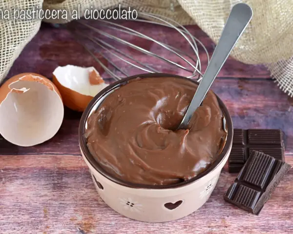 Crema pasticcera al cioccolato, liscia e invitante, pronta per essere gustata. Uova, frusta e cioccolato, ingredienti per un dolce momento.