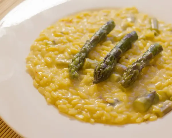 Risotto cremoso con asparagi e zafferano, un piatto primaverile che profuma di sole.
