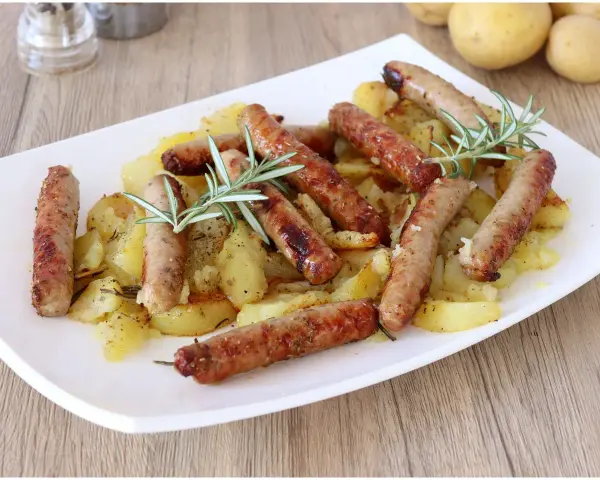 Salsiccia e patate al forno, un piatto rustico e saporito, con rosmarino fresco che profuma il tutto.