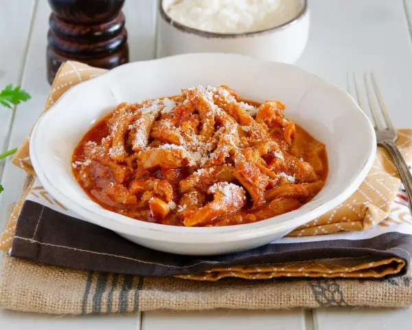 Un invitante piatto di trippa alla parmigiana, cosparso di formaggio grattugiato, pronto per essere gustato.