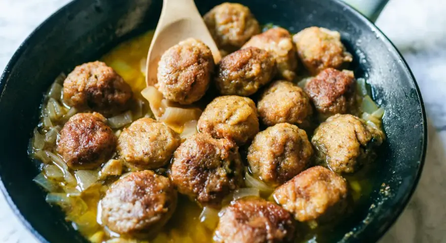 Polpette dorate in padella con cipolle, pronte per essere gustate. Un classico della cucina italiana.