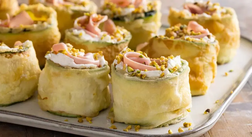 Rotolini di zucchine fritte con crema, prosciutto e pistacchi: stuzzichini veloci ed economici per aperitivo, perfetti per stupire gli ospiti.