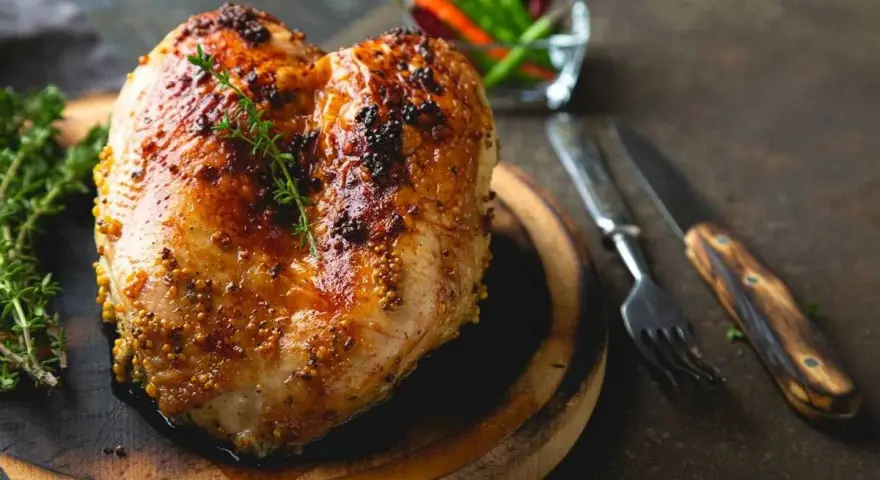 Petto di pollo al forno dorato e succulento, condito con senape e erbe aromatiche, pronto per essere gustato.