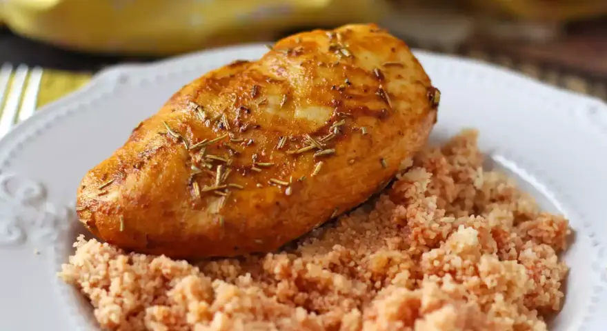 Petto di pollo in friggitrice ad aria, dorato e aromatico, servito su un letto di couscous.