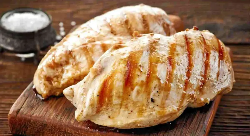 Petto di pollo alla griglia, perfetti secondi di carne da preparare in anticipo. Un contorno di sale completa l'immagine.
