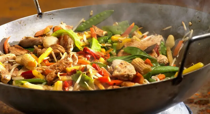 Straccetti di pollo saltati in padella con verdure colorate: piselli, carote, peperoni e germogli.