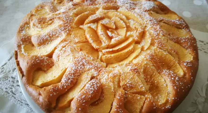 Deliziosa torta di mele senza glutine, decorata con mele a forma di rosa e spolverata di zucchero a velo.