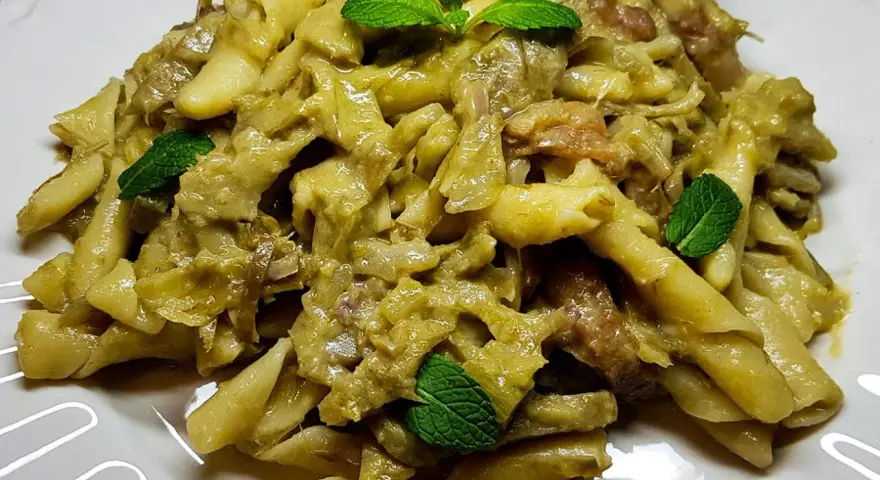 Pasta con carciofi cremosa, guarnita con foglie di menta fresca. Un piatto saporito e invitante.