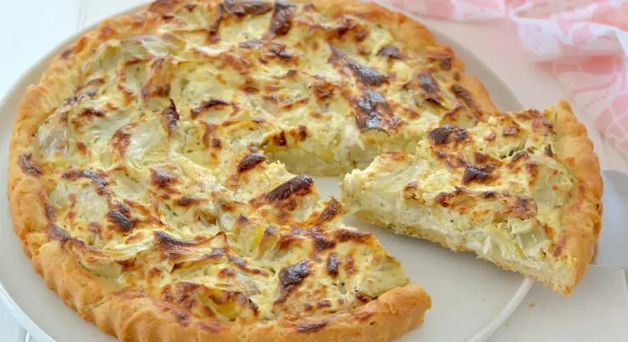 Una deliziosa torta salata con carciofi, dorata e invitante, con una fetta appena tagliata che mostra il ripieno cremoso.