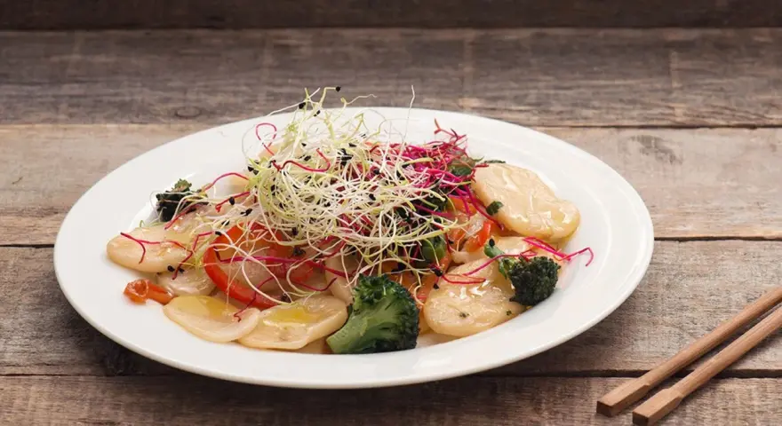 Gnocchi di riso con verdure croccanti e germogli freschi, un piatto leggero e colorato.