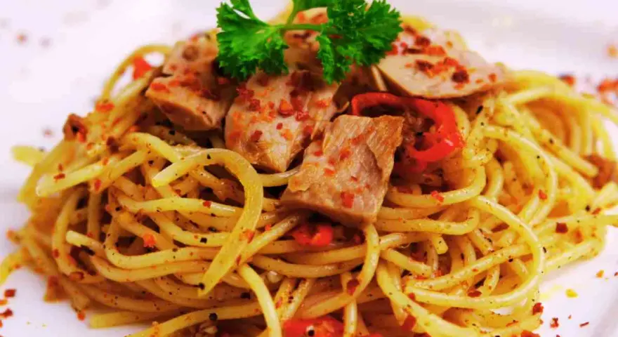 Spaghetti conditi con tonno fresco, peperoncino e prezzemolo. Un piatto semplice e gustoso.