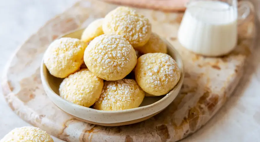 Biscotti da inzuppo spolverati di zucchero a velo in una ciotola, pronti per essere gustati con un bicchierino di latte.