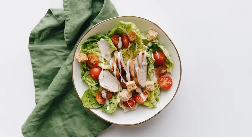 Deliziosa insalata di pollo con lattuga croccante, pomodorini succosi e crostini, condita con una cremosa salsa.