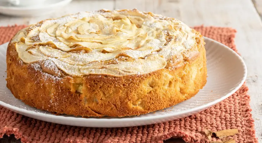 Deliziosa torta di mele senza burro, con mele a rosa sulla superficie e una spolverata di zucchero a velo. Perfetta per una colazione leggera.