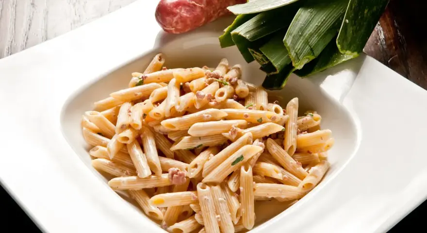 Penne cremose con salsiccia e verdure, un piatto di pasta alla norcina pronto per essere gustato.