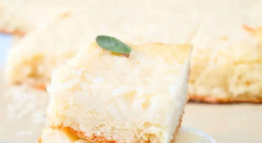 Una fetta di torta di riso carrarina, soffice e profumata, guarnita con una fogliolina verde.