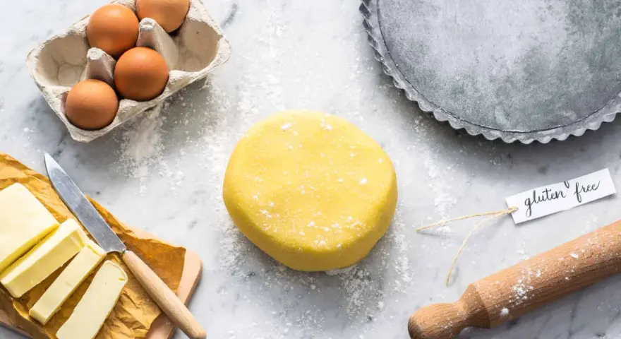 Impasto giallo brillante per una deliziosa pasta frolla senza glutine, pronto con uova, burro e una teglia.