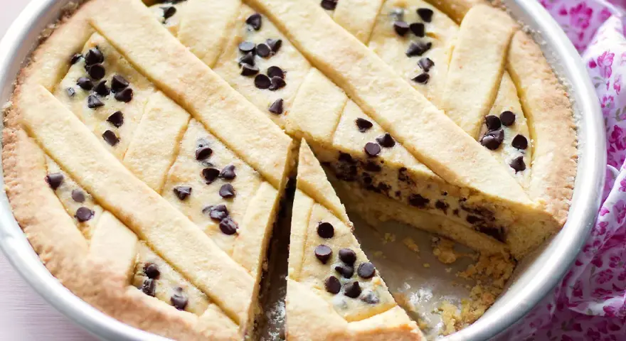 Deliziosa crostata ricotta e cioccolato con un reticolo di pasta frolla e gocce di cioccolato fondente.
