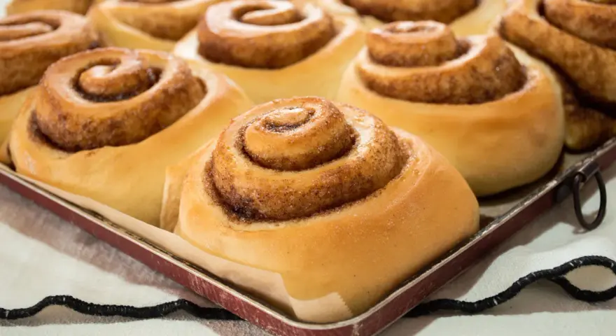 Dolci cinnamon rolls appena sfornati, pronti per essere gustati. Una ricetta perfetta per la colazione o la merenda.
