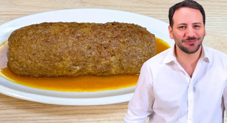 Un uomo sorride accanto a un succulento polpettone in padella, pronto per essere gustato.