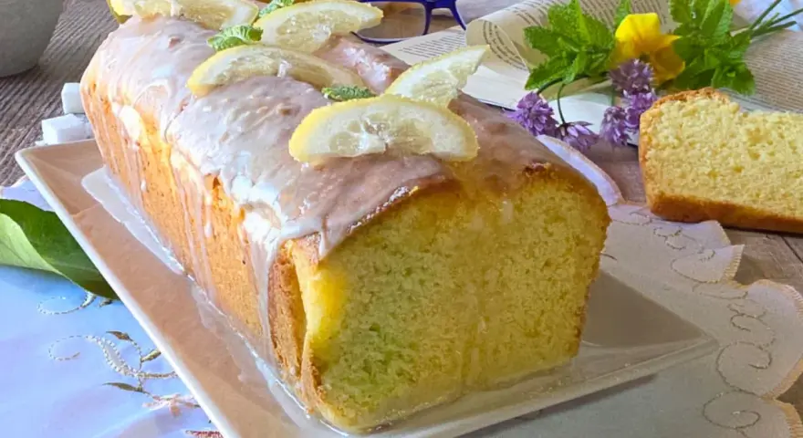 Un soffice plumcake al limone glassato, decorato con fette di limone e menta. Perfetto per una pausa golosa.