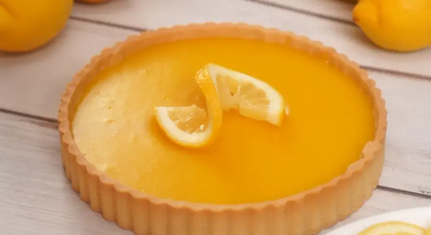 Una deliziosa crostata al limone, con la sua crema gialla brillante e decorata con spicchi di limone fresco.