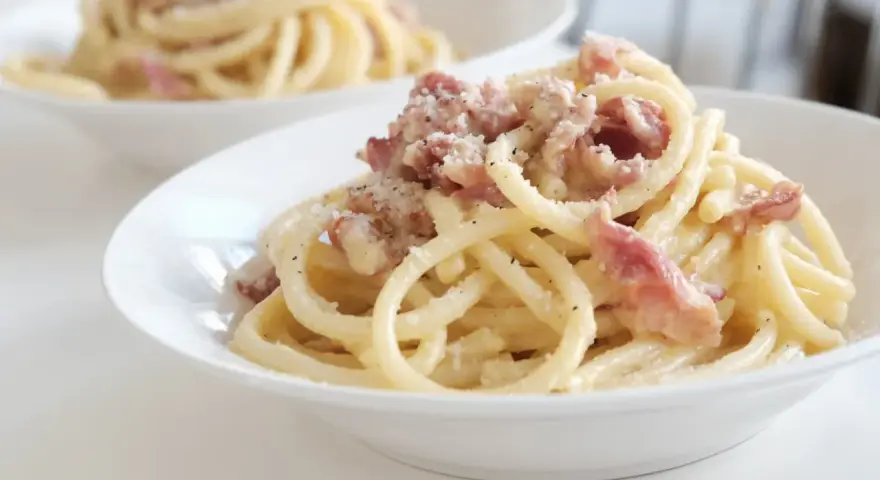 Un piatto di pasta alla gricia fumante, con guanciale croccante e pecorino romano grattugiato.