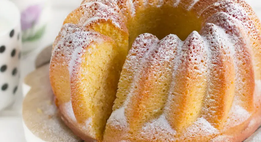 Un soffice ciambellone allo yogurt, cosparso di zucchero a velo, pronto per essere gustato.