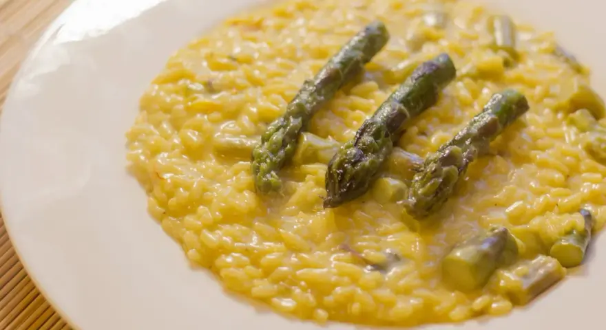 Risotto cremoso con asparagi e zafferano, un piatto primaverile che profuma di sole.