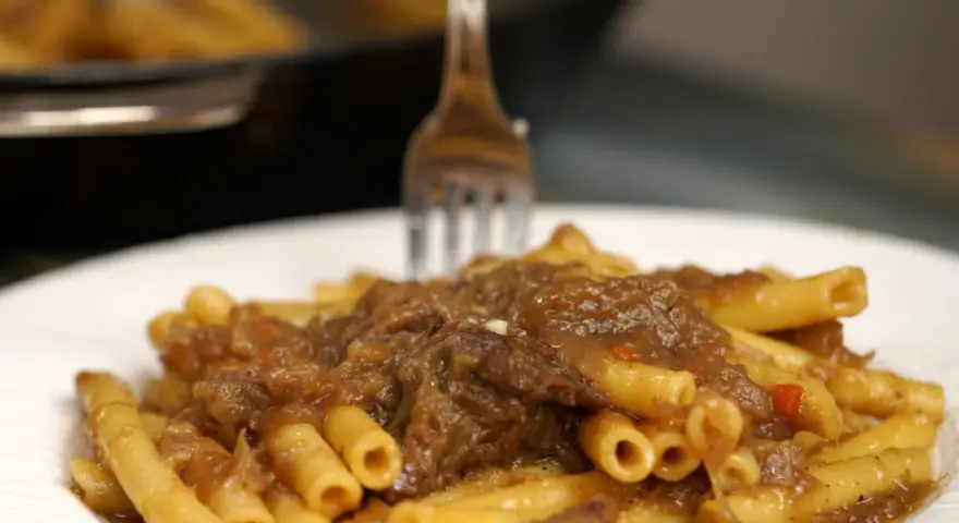 Un piatto invitante di ziti alla genovese, con la pasta che abbraccia un ricco ragù di carne e cipolle.